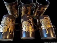 Six coffee mugs displayed showing gold medieval themed illustrations against a dark brown matte background, each mug unique design.