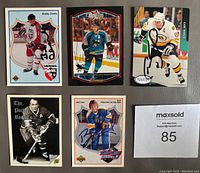 Photo shows 5 autographed NHL hockey cards including Brett Hull, Cam Neely, Bobby Clarke, Henri Richard signed in Sharpie, arranged on a flat surface with a lot number card.