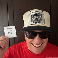 Front view of cap worn on head showing embroidered lynx face patch and black brim