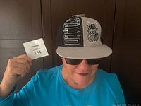 Person wearing the Ottawa Lynx baseball cap with black and gray panels, showing the front with embroidered logo and snapback visible from the back.