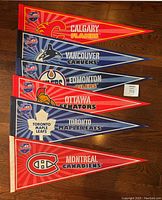 Photo showing the full set of six pennants arranged from top to bottom: Calgary Flames, Vancouver Canucks, Edmonton Oilers, Ottawa Senators, Toronto Maple Leafs, Montreal Canadiens.