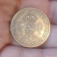 Reverse side of the 1948 English 2 Shilling coin showing crowned Tudor rose, thistle, shamrock, denomination and year.