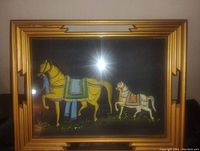Framed antique Asian silk painting showing two horses on black background, front view with glare from light source.