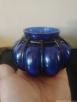 Cobalt blue glass candle holder in black iron cage, shown resting on a surface.