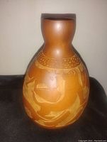 Front view of the hand carved gourd vase showing detailed animal design.