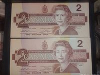 Front view of two 1986 Canadian 2 dollar bills stacked, showing Queen Elizabeth II portrait and denomination details.
