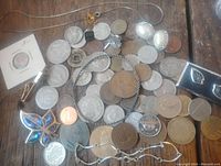 Photo of mixed vintage coins and assorted jewelry including bracelets, earrings, brooch, ring, cufflinks, pendant, and chain.