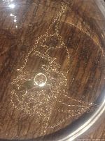 Full view of gold chain necklace showing chain link pattern and overall length layout on wooden surface.