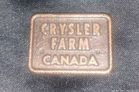 Close-up front side view of a rectangular bronze bar with raised text 'Chrysler Farm Canada'.