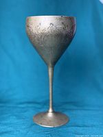 Engraved goblet showing floral and circular patterns with tarnishing