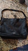 Full front view of used black leather purse with shoulder strap
