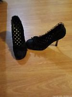 Two black Wild Diva women's heels size 5.5 placed on a wooden floor. The heels have mesh polka dot design and ruffled trim detail.