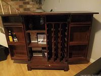 Mini bar cabinet opened showing wooden wine rack and shelves inside