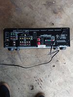 Rear view of Onkyo stereo receiver showing multiple audio input/output connections and speaker terminals with an attached cord.