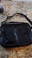 Front view of black Swiss-Gear laptop bag showing zippered pocket with logo and shoulder strap