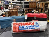 Two tool boxes side by side with Husky plastic sheeting roll in front