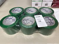 Front view of 6 green XL rolls of shipping tape, shrink-wrapped in two rows of three.