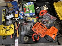 Wide overview of all tools showing the assortment including hammer, levels, saw, caulking gun, flashlight, and bits