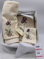 Photo of the full towel set in a box showing bath towel, hand towel, and washcloth with embroidery.