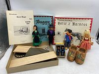 Wide view of entire lot showing dolls, wooden Dutch shoes, buggy kit, and harness box