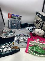 Grouping of five Eagles T-shirts, Eagles cooler bag, Super Bowl mini football, and Eagles paper gift bag.