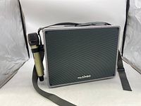 Front view showing karaoke machine with mesh speaker and black wireless microphone hanging on the side