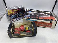 Three model kits including Revell Corvette SnapTite sealed kit, Goodyear Blimp box with wear, and Liberty Classics 1947 Pickup collectible in display case.