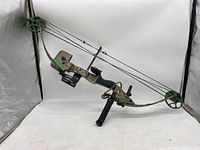 Full view of the Odyssey II compound hunting bow showing the camouflage riser, green cams, black grip, stabilizer, and sight.