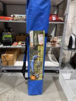 Photo of the canopy tent storage bag with a product label showing the tent setup with three people underneath.