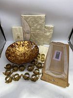 Full view of Lenox tablecloth and napkins, IVV glass bowl, serving tray in packaging, brass napkin rings and napkin holders.