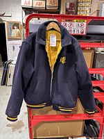 Navy blue wool side of jacket with embroidered yellow 'RL' logo on chest, ribbed cuffs and hem, hanging on red rack