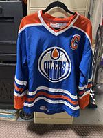 Front view of the vintage Edmonton Oilers hockey jersey with Wayne Gretzky captain patch and team logo in blue, orange, and white colors.
