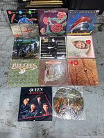Photo showing all 11 vintage vinyl record albums arranged on floor, various cover art styles visible