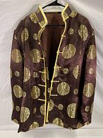 Front view of the brown silk jacket with gold Asian motif circles and yellow trim with button closures