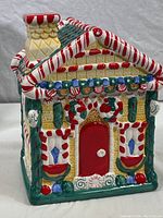Front and partial side view of the ceramic candy house cookie jar showing colorful candy details and red door.