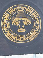 Close-up of the gold ink Tlingit Chilkat sun symbol etching on dark paper, showing intricate design details.