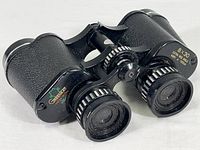 Photo showing the front and top view of the Greenkat 8x30 binoculars with logo and lens details visible.