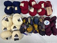 Full lot of yarn skeins in various colors shown together on a white surface