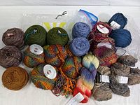 Multiple skeins of yarn laid out showing color variety and textures including bulky and fine yarns