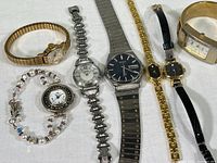 Full view of seven quartz watches with different bands and styles arranged side by side.