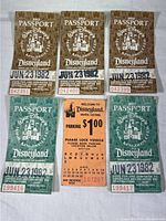 Front view of six 1982 Walt Disney passports and one Disneyland parking pass, showing detailed serial numbers, date stamps and logos.