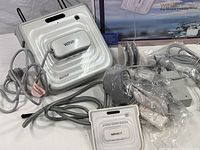 Main white square Winbot W730 window cleaning robot with attached cables and accessories viewed on table, showing design and cables.