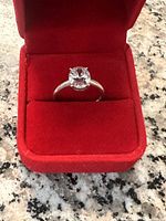 close-up view of 10k white gold ring with solitaire diamond in red velvet box