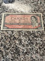 Front side of 1954 Canadian $2 bill showing Queen Elizabeth II portrait, serial numbers, and denomination text.