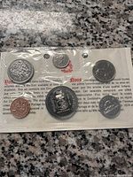 1974 Canadian coins sealed in original packaging showing front side with the penny, nickel, quarter, and silver dollar under original holder on a granite surface.