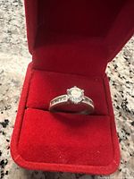 Top view of sterling silver ring with clear center stone in red velvet box