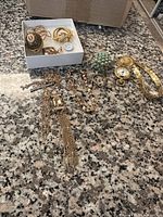 Full view of all jewelry items laid out on granite surface, showing watch, rings, brooch, necklaces and bracelets.