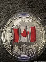 Obverse side of the Canadian silver coin with colored flag and inscriptions.