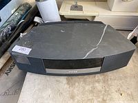 Bose Wave Music System II with visible scratches and marks on top surface placed on a workshop table.