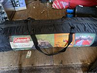 Coleman 10ft x 9ft instant tent in black carry bag with product label visible showing size and brand.